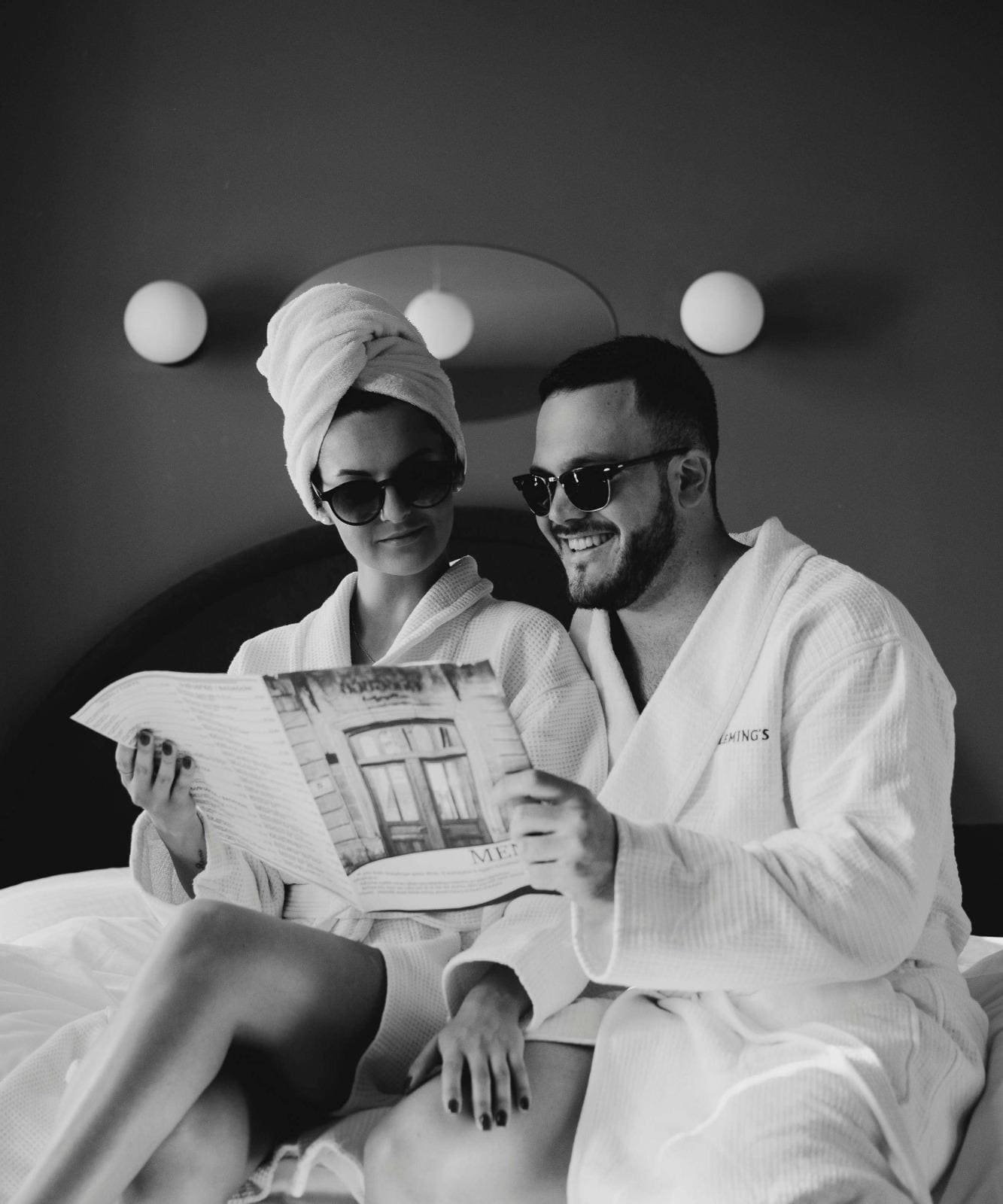 A couple in robes enjoys reading a magazine in a stylish hotel room, creating a sense of luxury and relaxation.